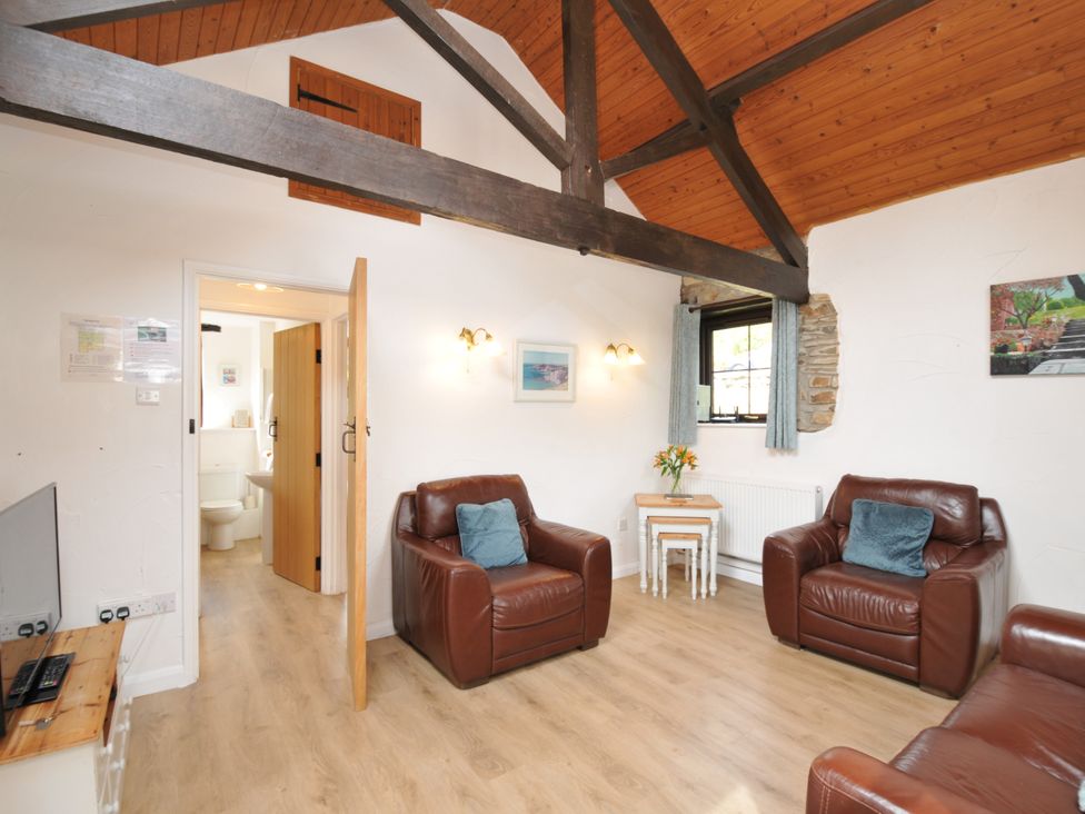A living room with brown sofas and a door leading to a bathroom at Shipload Cottage in Hartland