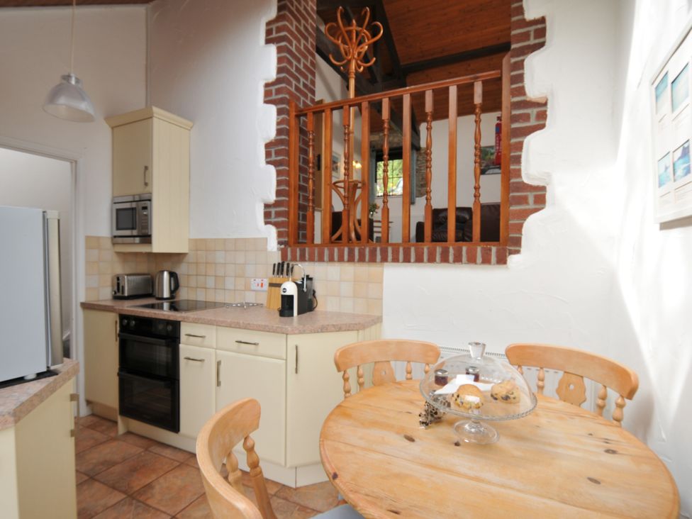 A kitchen with appliances and a dining table at Shipload Cottage Hartland