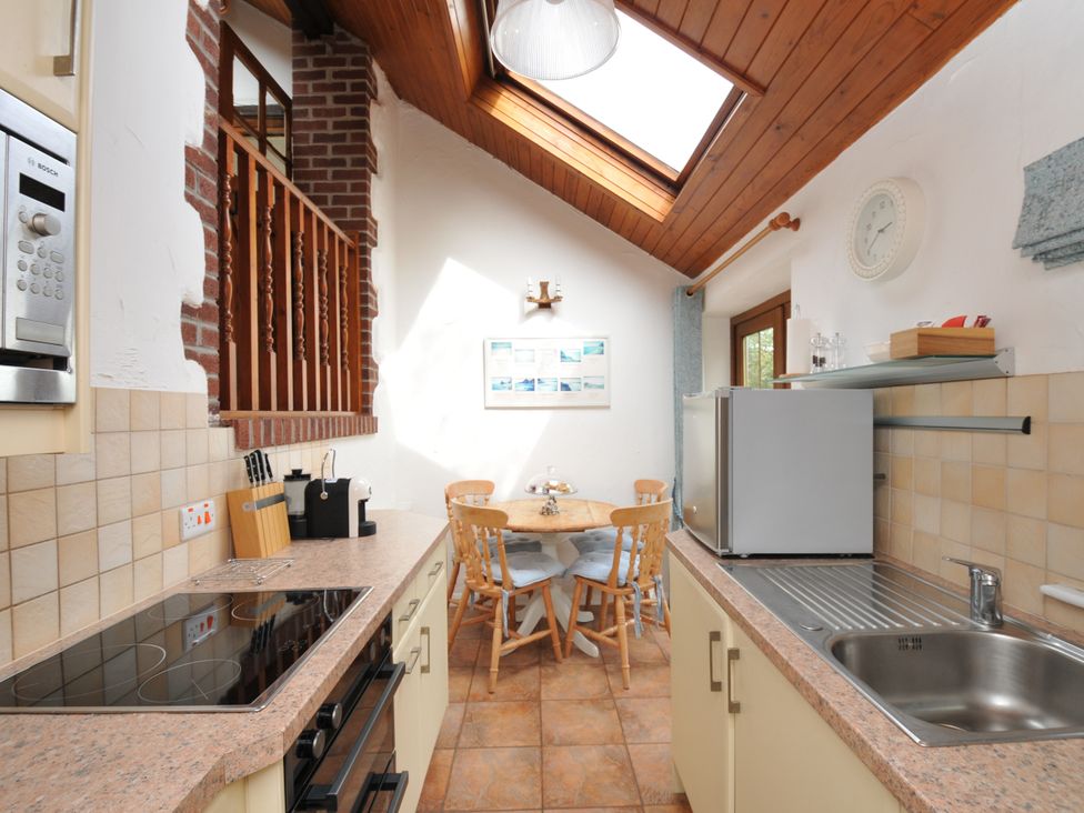 A kitchen with appliances and dining area at Shipload Cottage Hartland