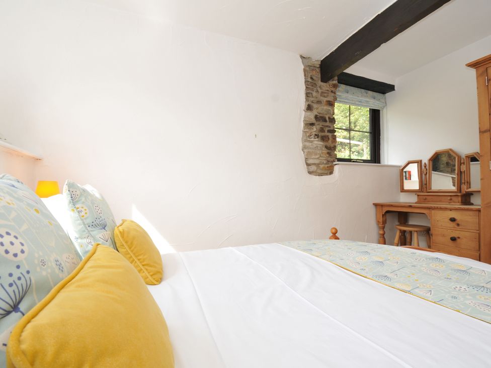 A bedroom with a bed and dressing table at Shipload Cottage in Hartland