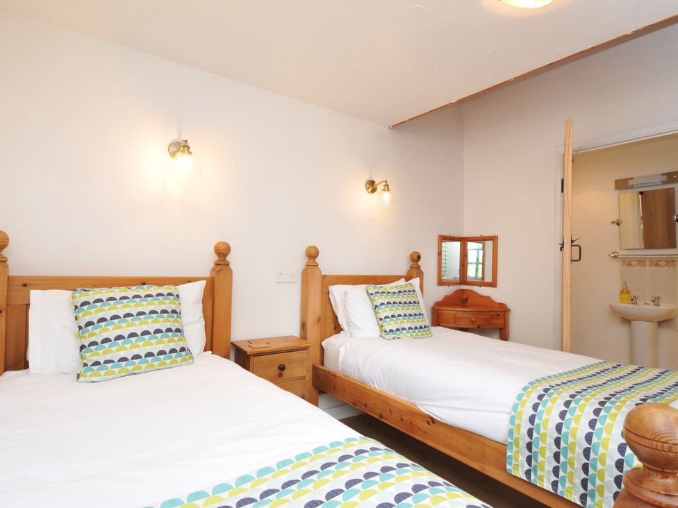 A bedroom with two beds and a wash basin at Shipload Cottage Hartland