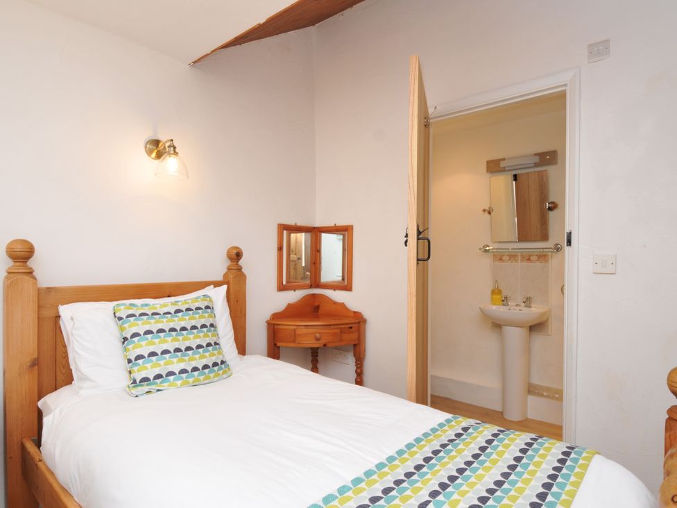 A bedroom with a bed and an attached bathroom at Shipload Cottage in Hartland