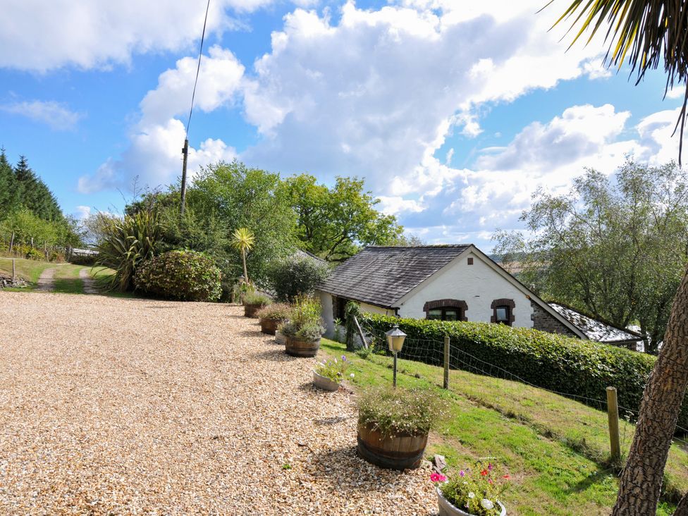 An outdoor view of a house with a gravel driveway and garden at Shipload Cottage, Hartland