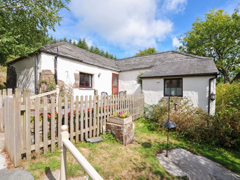 A cottage surrounded by a fence and flower bed at Windbury Cottage in Hartland