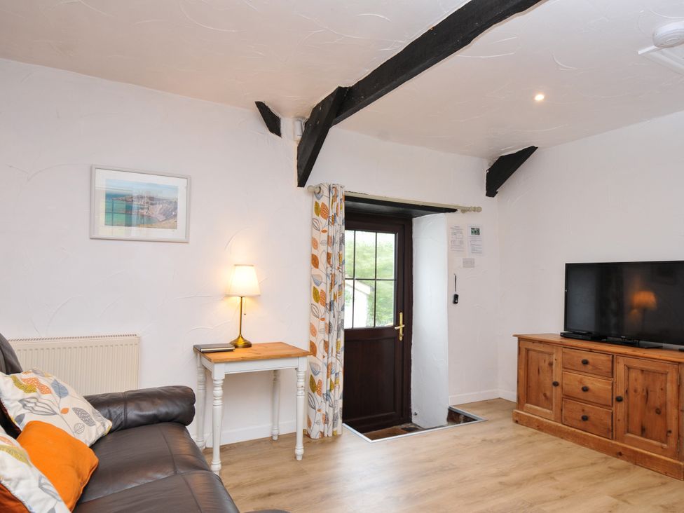 A living room with a sofa and television at Windbury Cottage in Hartland