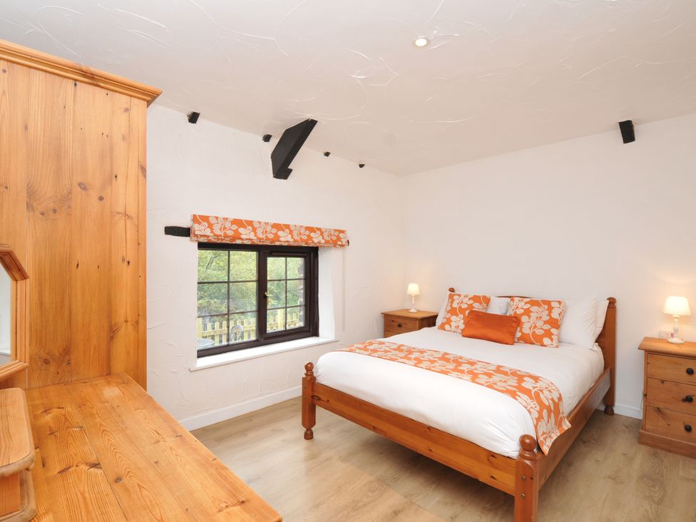 A bedroom with a bed and wooden furniture at Windbury Cottage in Hartland