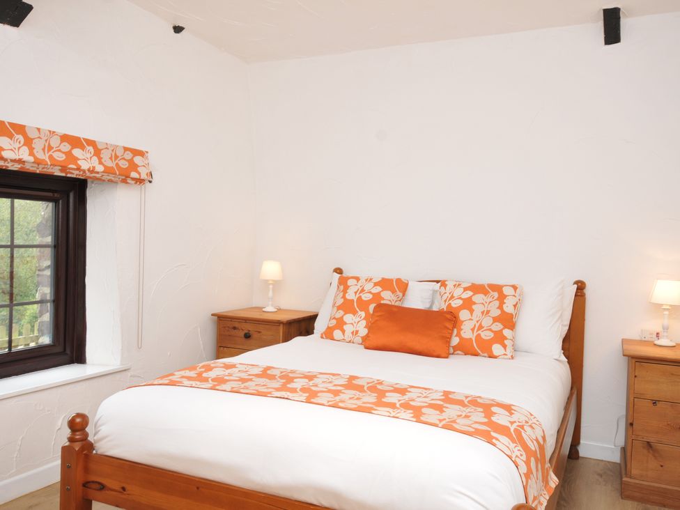 A bedroom with a bed and nightstands at Windbury Cottage in Hartland