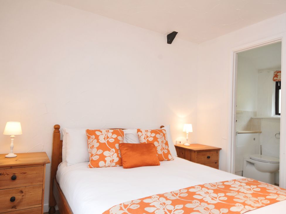 A bedroom with a bed and nightstand at Windbury Cottage in Hartland