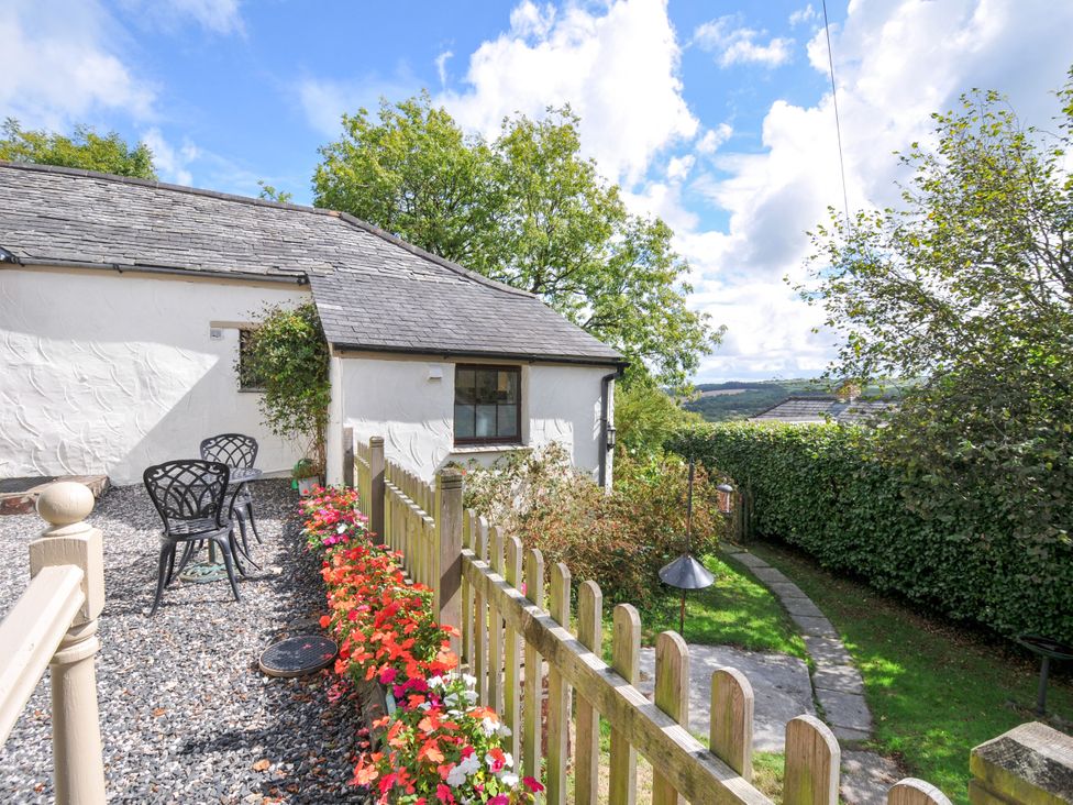 An outdoor area with chairs and flowers at Windbury Cottage in Hartland