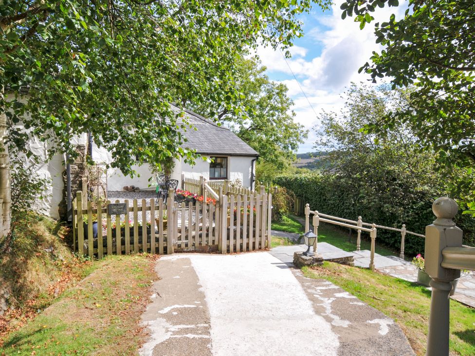 An outdoor view of a house with a fence and flowers at Windbury Cottage in Hartland