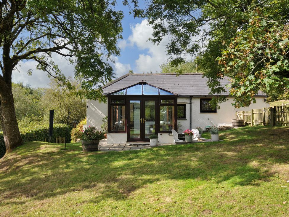 A backyard with a conservatory and planters at Barley Cottage in Hartland