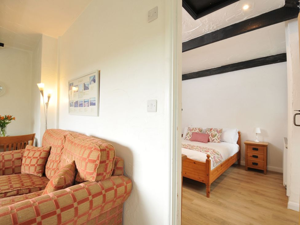 A living room with a sofa and a view of a bedroom at Barley Cottage in Hartland
