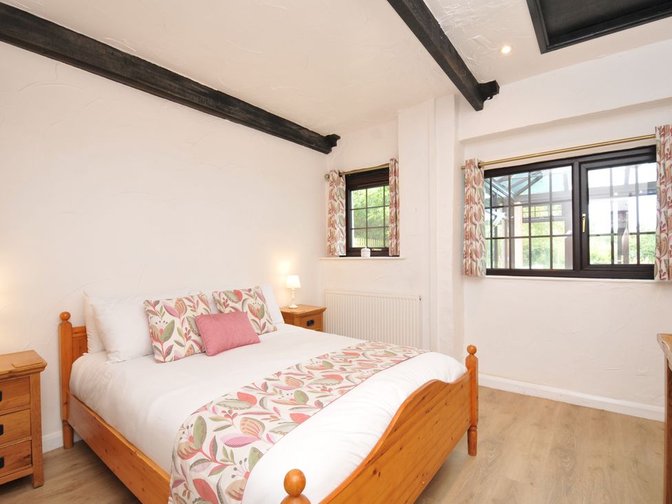 A bedroom with a bed and nightstand at Barley Cottage in Hartland