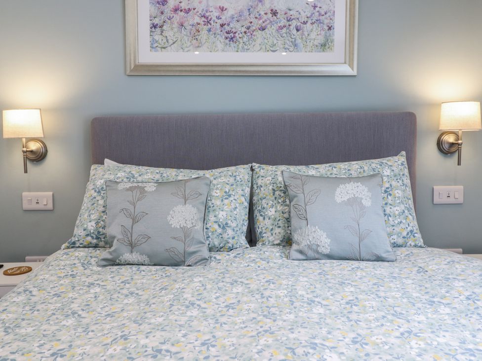 A bedroom with a bed and decorative pillows at Neptune Cottage in Conwy