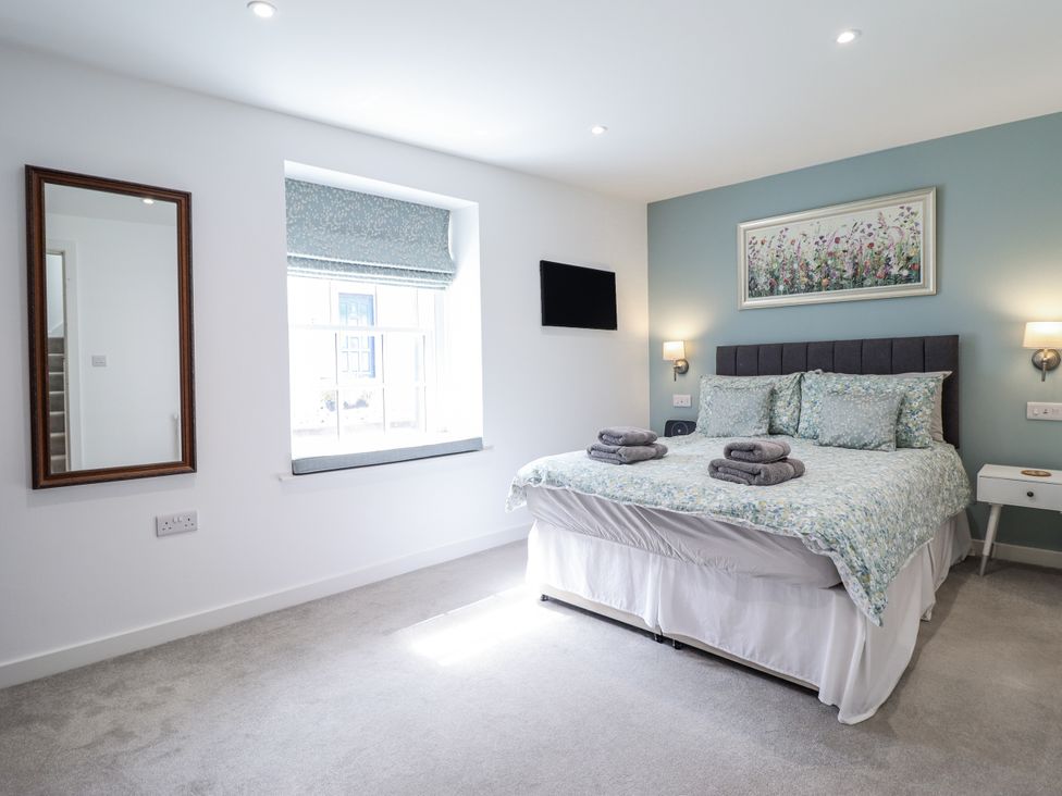 A bedroom with a bed and mirror at Neptune Cottage Conwy