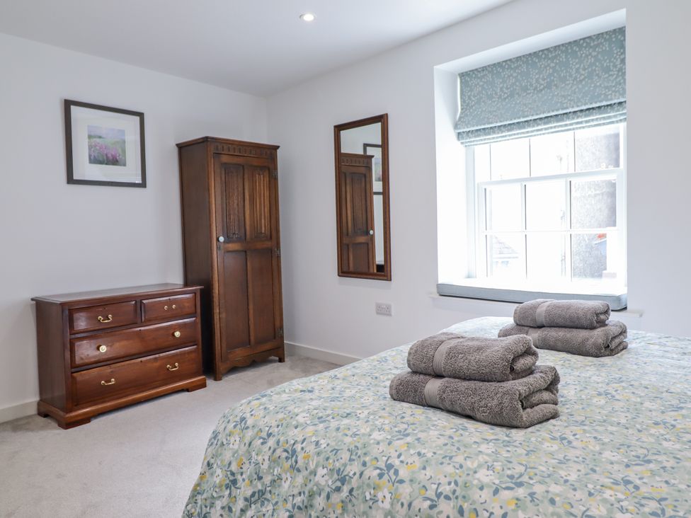 A bedroom with a bed and towels on top at Neptune Cottage in Conwy