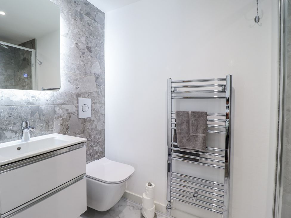 A bathroom with a sink, toilet, and towel rail at Neptune Cottage in Conwy