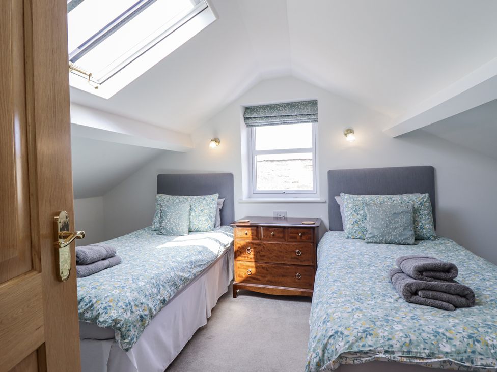 A bedroom with two beds and a nightstand at Neptune Cottage in Conwy
