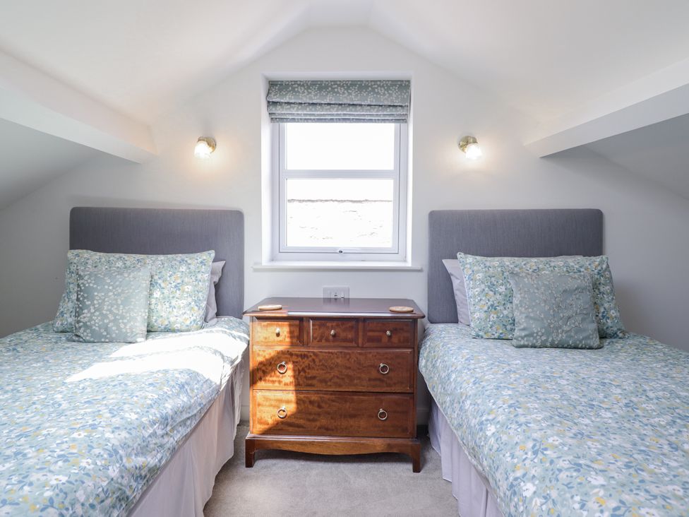 A bedroom with two beds and a wooden chest of drawers at Neptune Cottage in Conwy