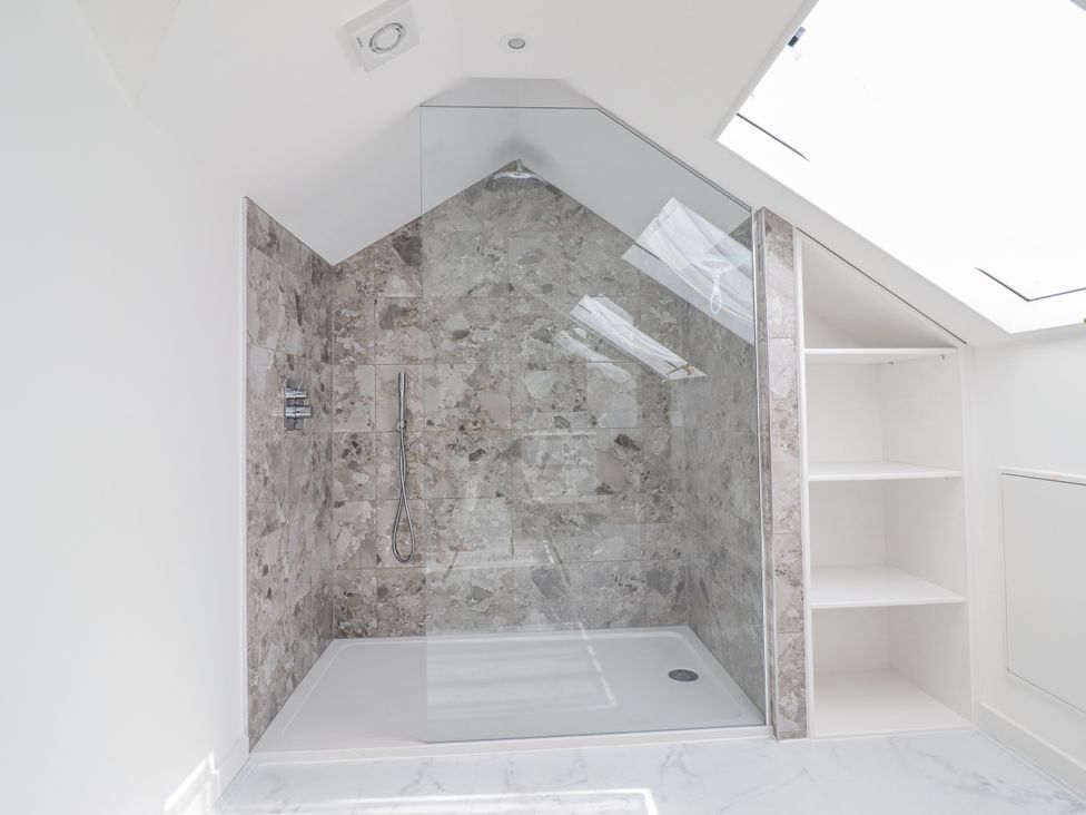 A shower with tiled walls and shelves at Neptune Cottage Conwy