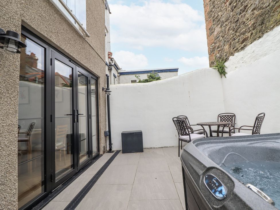 An outdoor area with a hot tub and seating at Neptune Cottage in Conwy