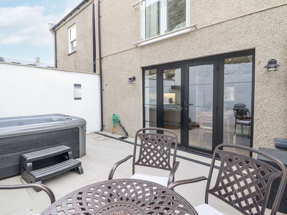 An outdoor area with a hot tub and a dining table at Neptune Cottage in Conwy