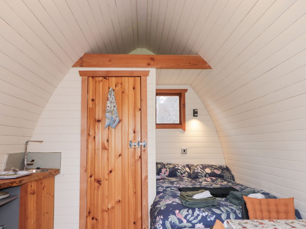 A bedroom with a bed and a door at Pod 2 in Beauly
