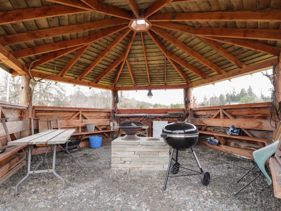 An outdoor seating area with a gazebo, table, and grill at Pod 2 in Beauly
