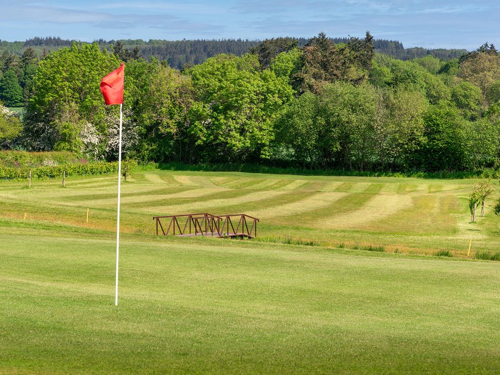 A golf course with a red flag and bridge at Mallard in Shobdon