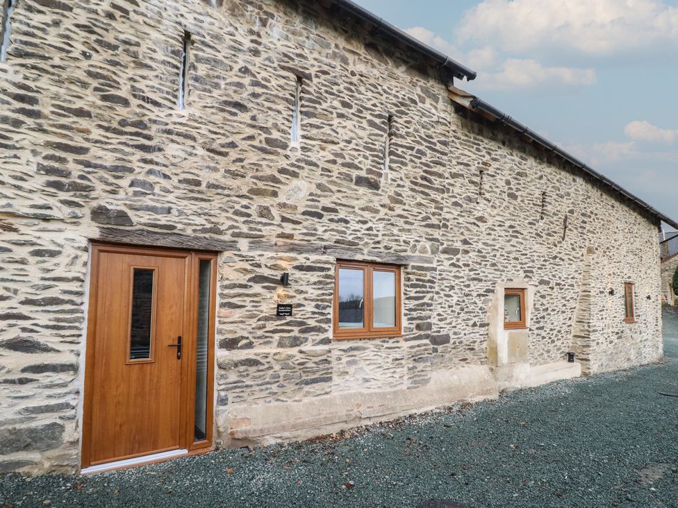 An exterior view of a stone building with wooden door and windows at Godre'r Gyrn, Plas Moelfre Hall Barns, Oswestry