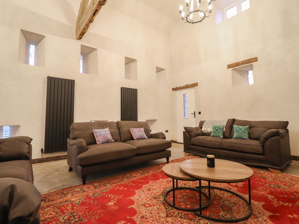 A living room with sofas, a coffee table, and a rug at Godre'r Gyrn, Plas Moelfre Hall Barns, Oswestry