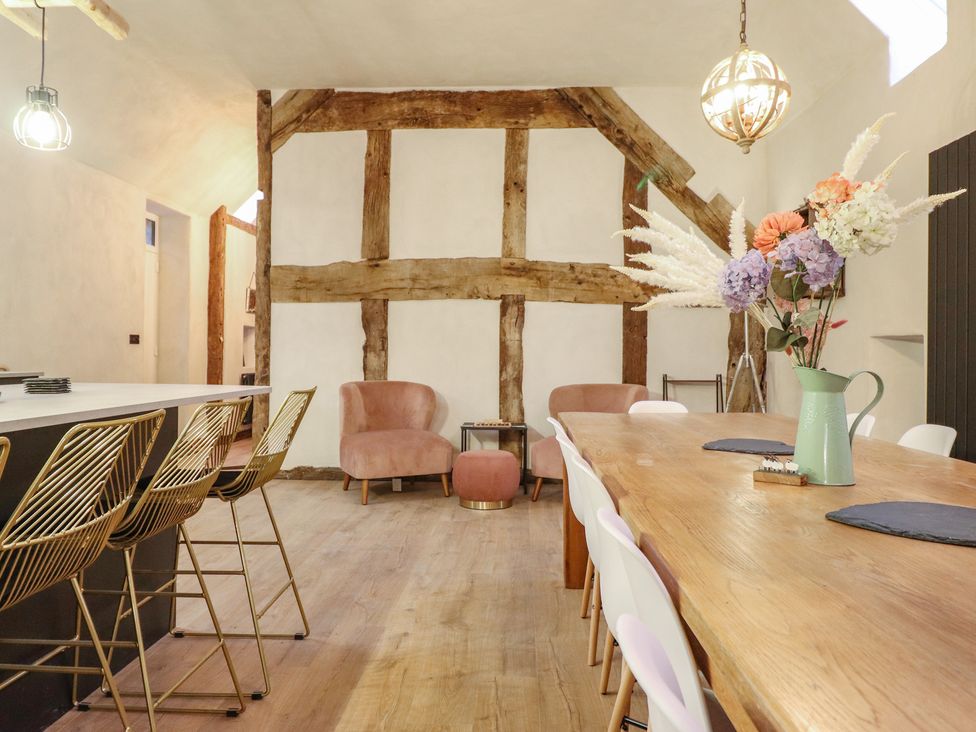 A dining room with a wooden table and bar stools at Godre'r Gyrn, Plas Moelfre Hall Barns, Oswestry