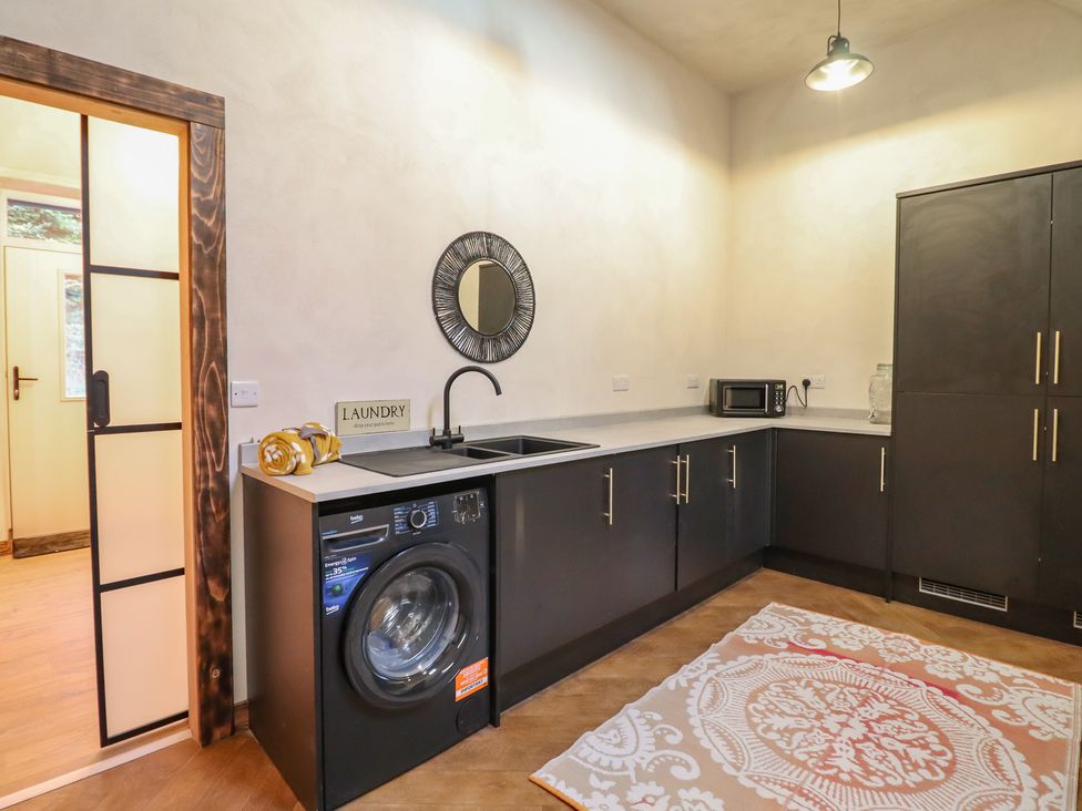 A laundry room with a washing machine and sink at Godre'r Gyrn, Plas Moelfre Hall Barns, Oswestry