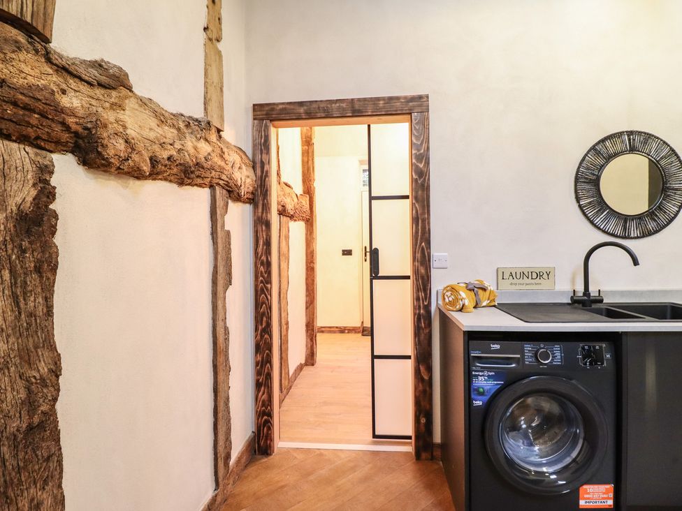 A laundry room with a washing machine and sink at Godre'r Gyrn, Plas Moelfre Hall Barns in Oswestry