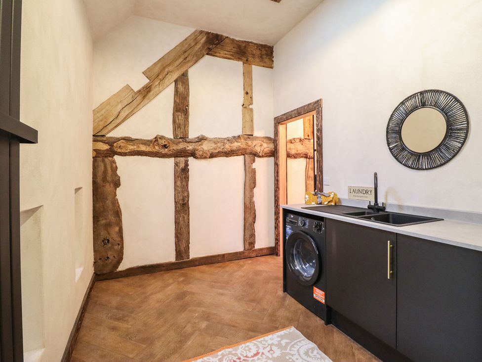 A laundry room with a washing machine and sink at Godre'r Gyrn, Plas Moelfre Hall Barns, Oswestry