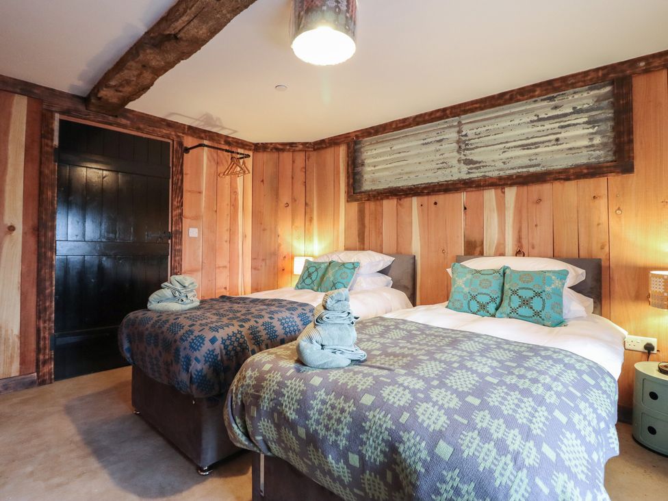 A bedroom with two beds and decorative towels at Godre'r Gyrn, Plas Moelfre Hall Barns, Oswestry