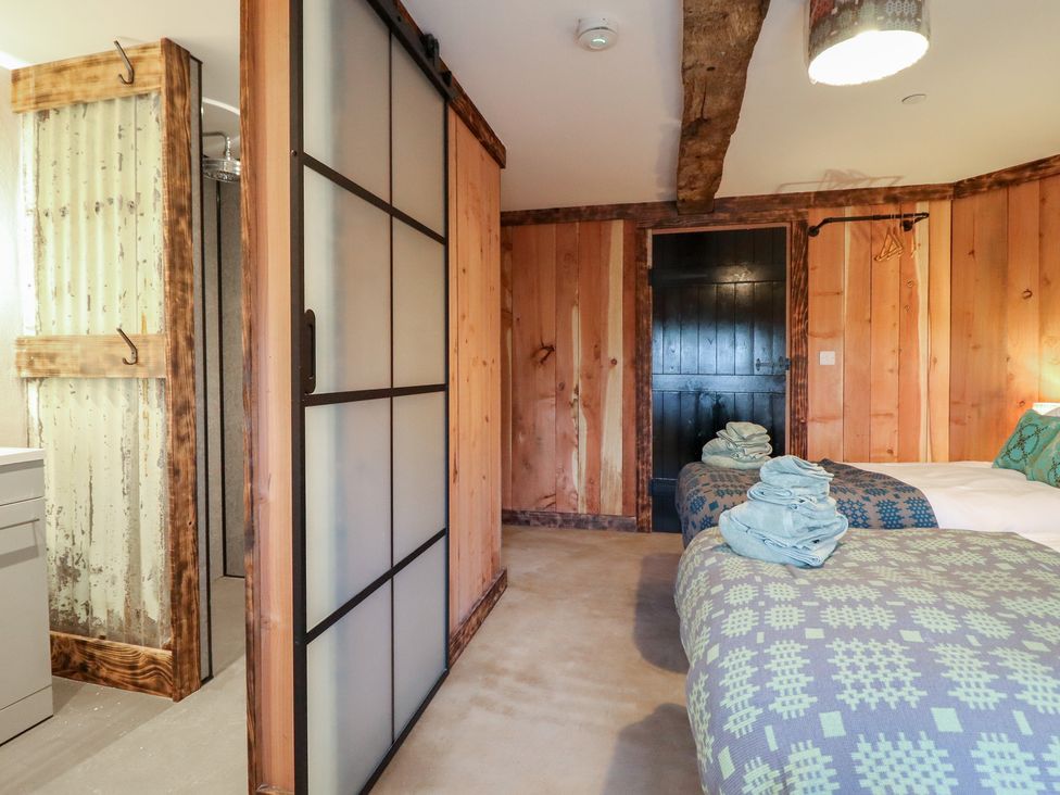 A bedroom with beds and a sliding door at Godre'r Gyrn, Plas Moelfre Hall Barns Oswestry