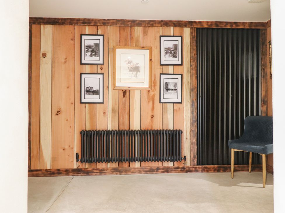A room with wood paneling, photographs on wall and a chair at Godre'r Gyrn, Plas Moelfre Hall Barns Oswestry