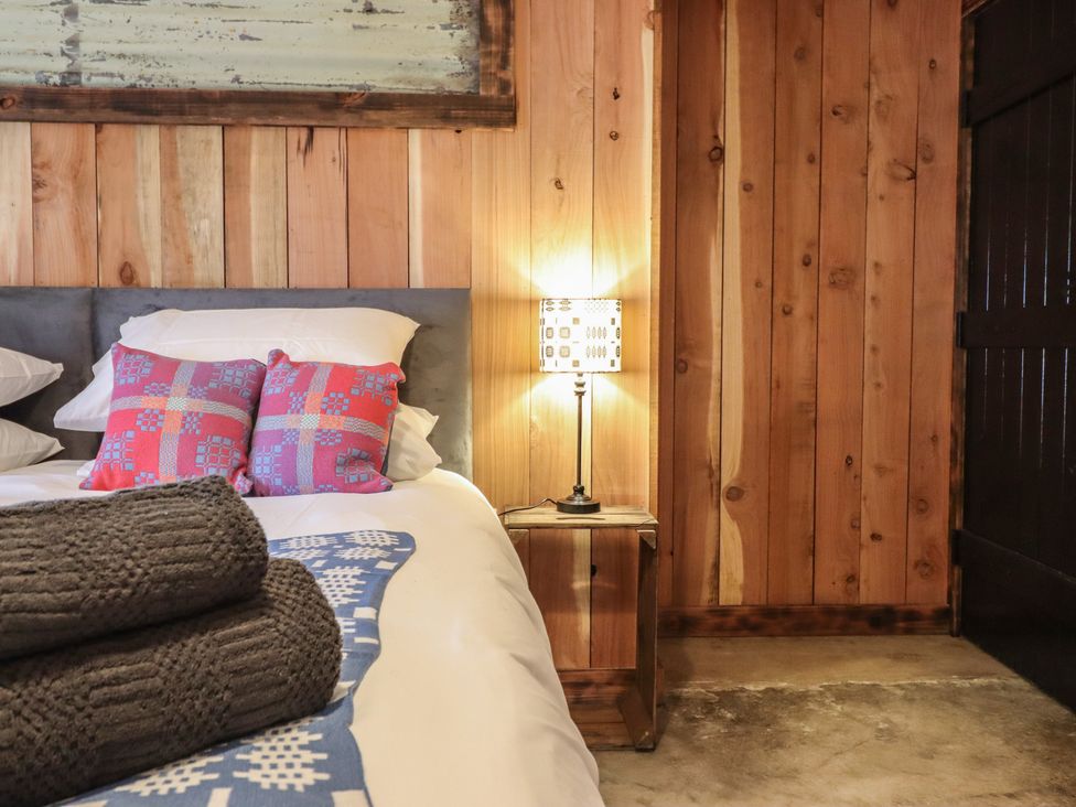 A bedroom with a bed and a lamp at Godre'r Gyrn, Plas Moelfre Hall Barns in Oswestry