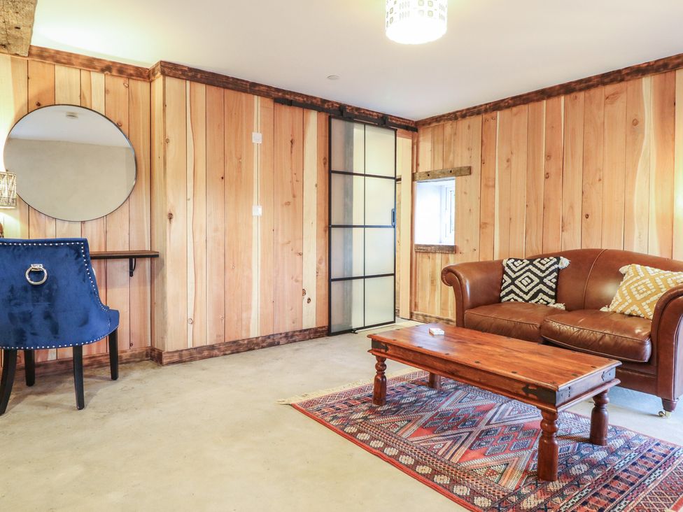 A living room with wood paneling and furniture at Godre'r Gyrn, Plas Moelfre Hall Barns, Oswestry