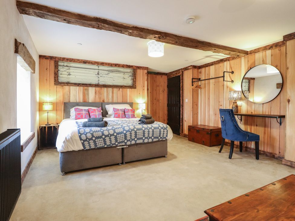 A bedroom with a bed, table, chair and lamp at Godre'r Gyrn, Plas Moelfre Hall Barns in Oswestry