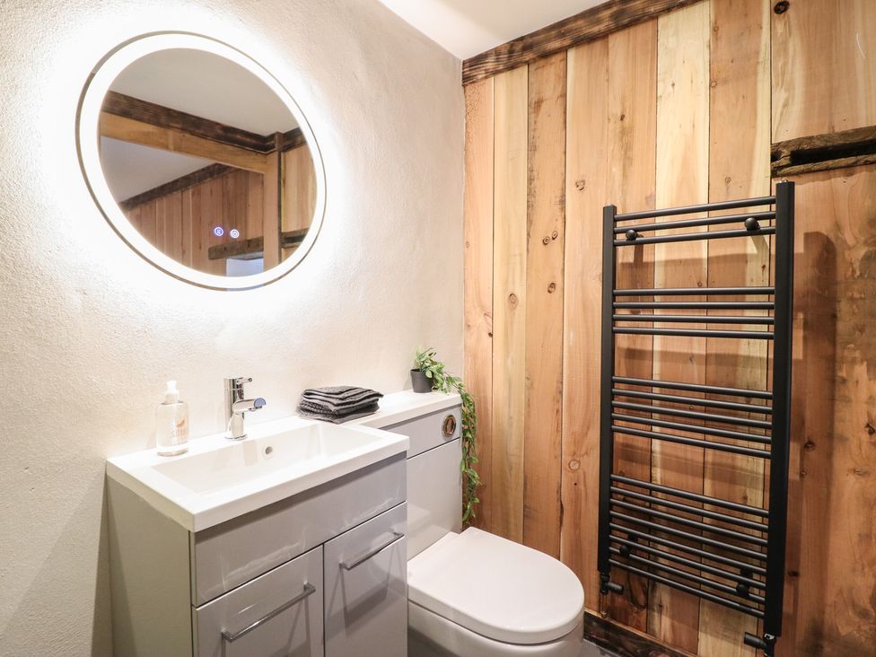 A bathroom with a sink, toilet, and towel rack at Godre'r Gyrn, Plas Moelfre Hall Barns, Oswestry