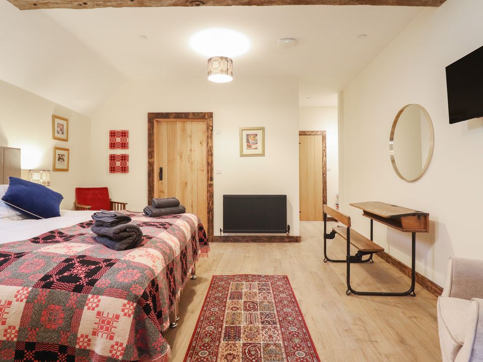 A bedroom with a bed, towels, and a side table at Godre'r Gyrn, Plas Moelfre Hall Barns in Oswestry