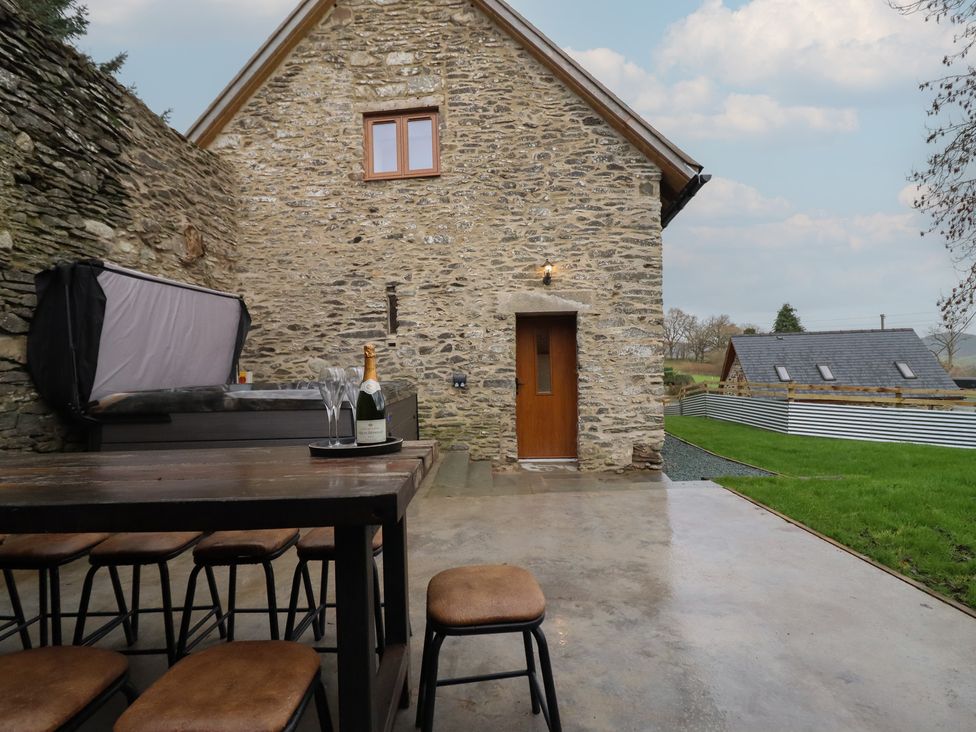 An outdoor area with a hot tub and table at Godre'r Gyrn, Plas Moelfre Hall Barns Oswestry