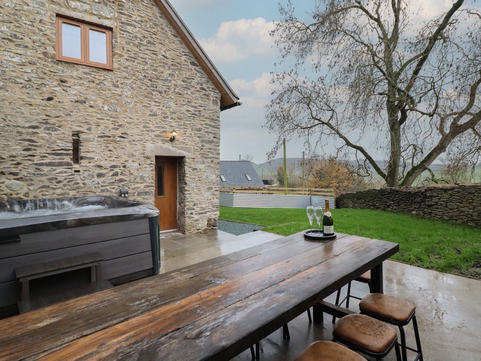An outdoor area with a hot tub and dining table at Godre'r Gyrn, Plas Moelfre Hall Barns, Oswestry