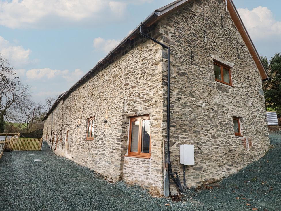 An exterior view of a stone building with windows and gravel area at Godre'r Gyrn, Plas Moelfre Hall Barns, Oswestry