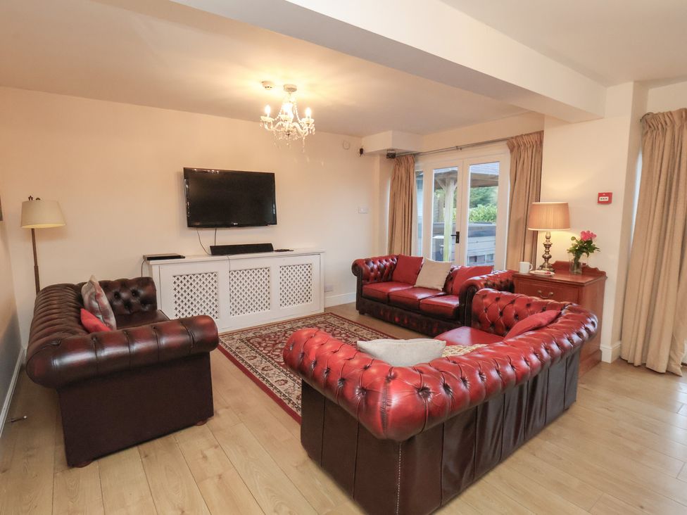 A living room with leather sofas and a television at Honeysuckle in Filey