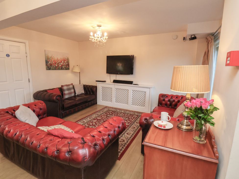 A living room with a sofa, table and television at Honeysuckle in Filey