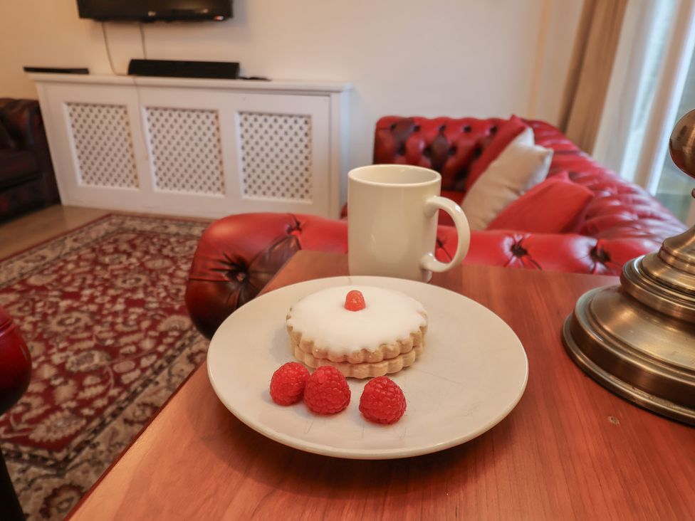 A tea cup and cake with raspberries on a coffee table at Honeysuckle in Filey