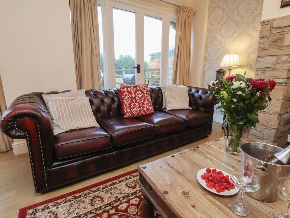 A living room with a sofa and flowers on a table at Honeysuckle in Filey
